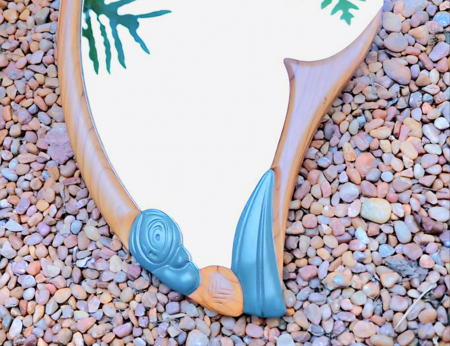 A wall-mounted mirror with a wooden frame and a reflective surface, featuring a nature-inspired design with a brown trunk and gray stones.