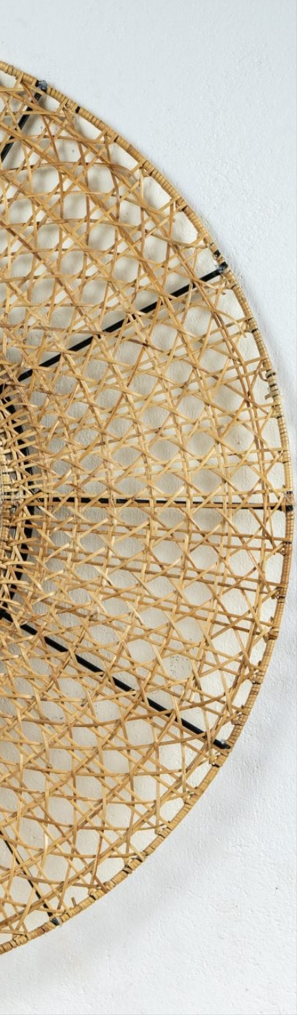 A round, handwoven honeycomb-inspired wall mirror made of natural rattan, mounted on a wall.