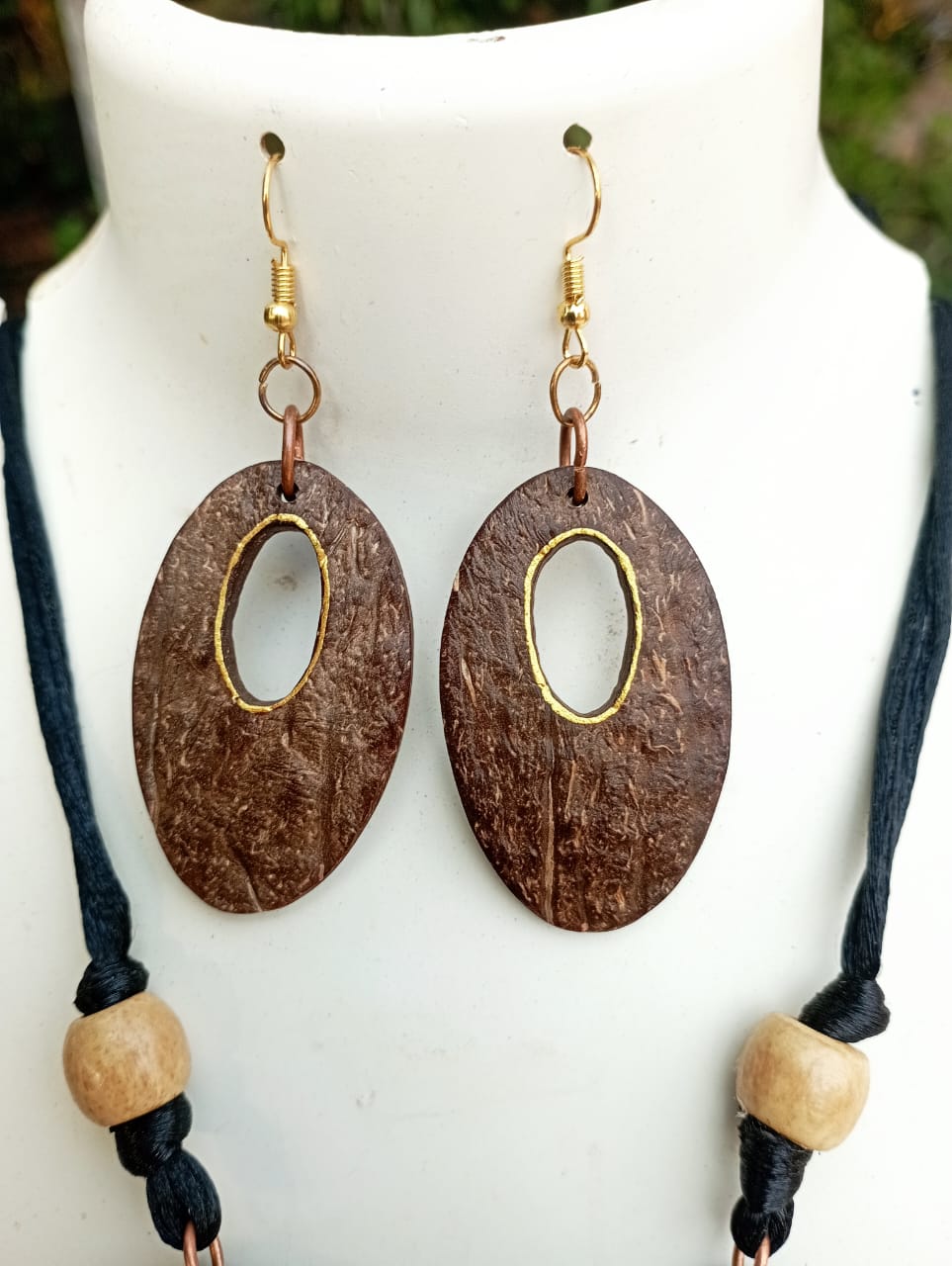 A necklace set with handcarved oval-shaped pendants made of coconut shell, displayed on a mannequin bust.