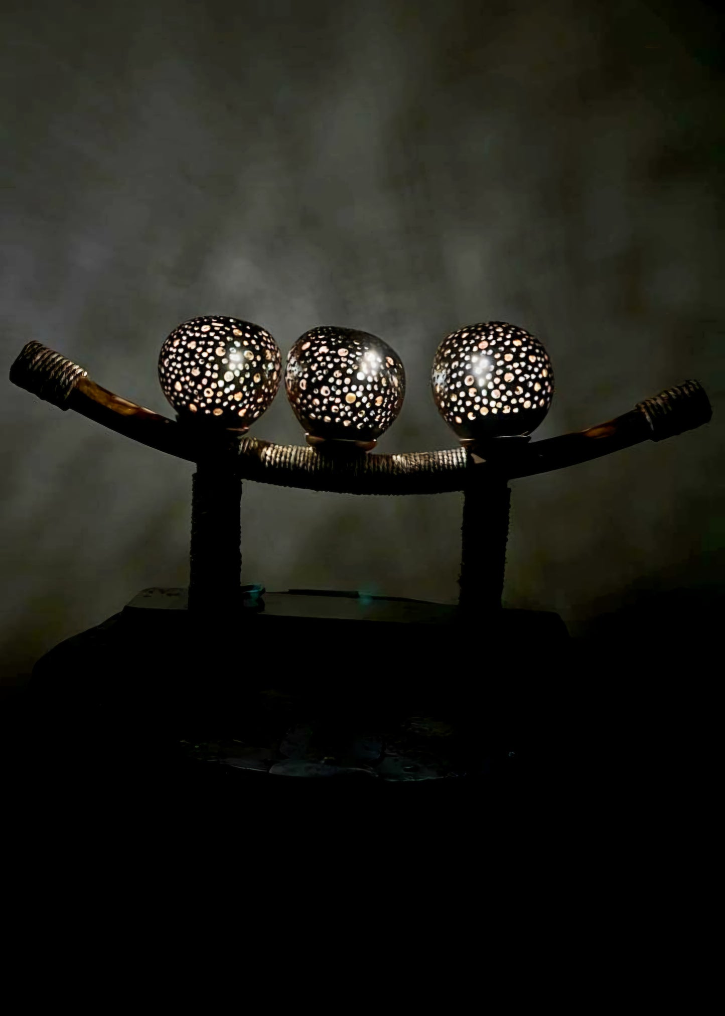 A three-ball lamp with a British colonial-styled shade, emitting a warm yellow light, placed on a wooden surface.