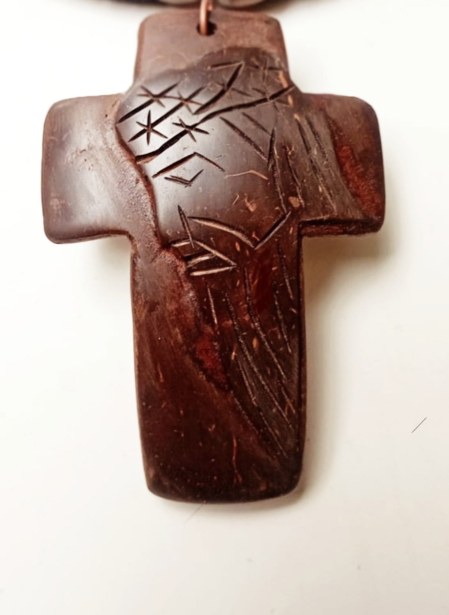 A brown crucifix pendant necklace with a black leather strap and coconut shell accents.