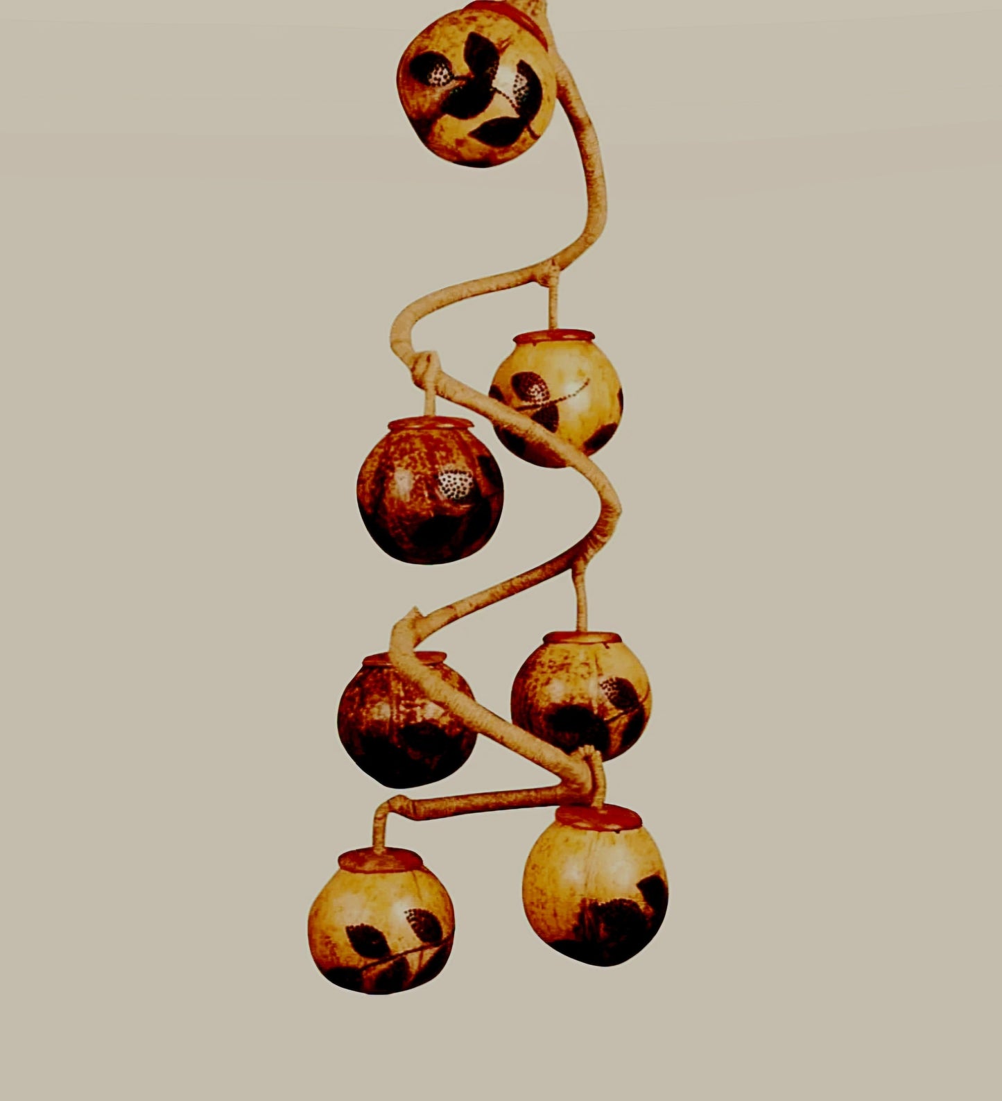 A hanging lamp with hand-carved ball lampshades that resemble grapes, with bulbs inside, mounted on a twisted wooden branch.