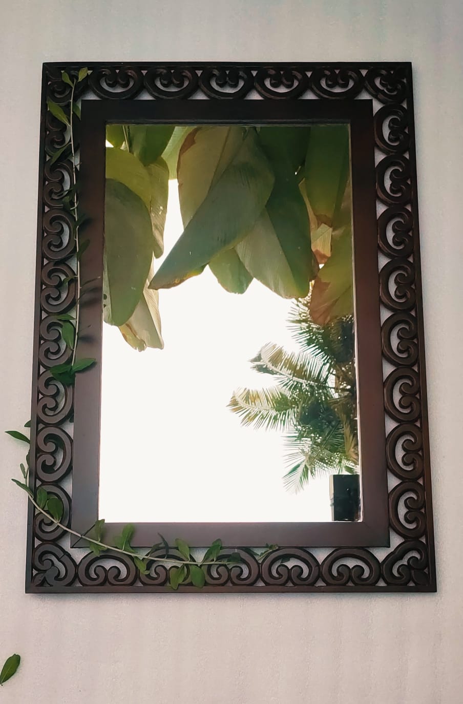 elegant wooden mirror features a beautifully crafted frame adorned with ancient floral motifs on all four sides.