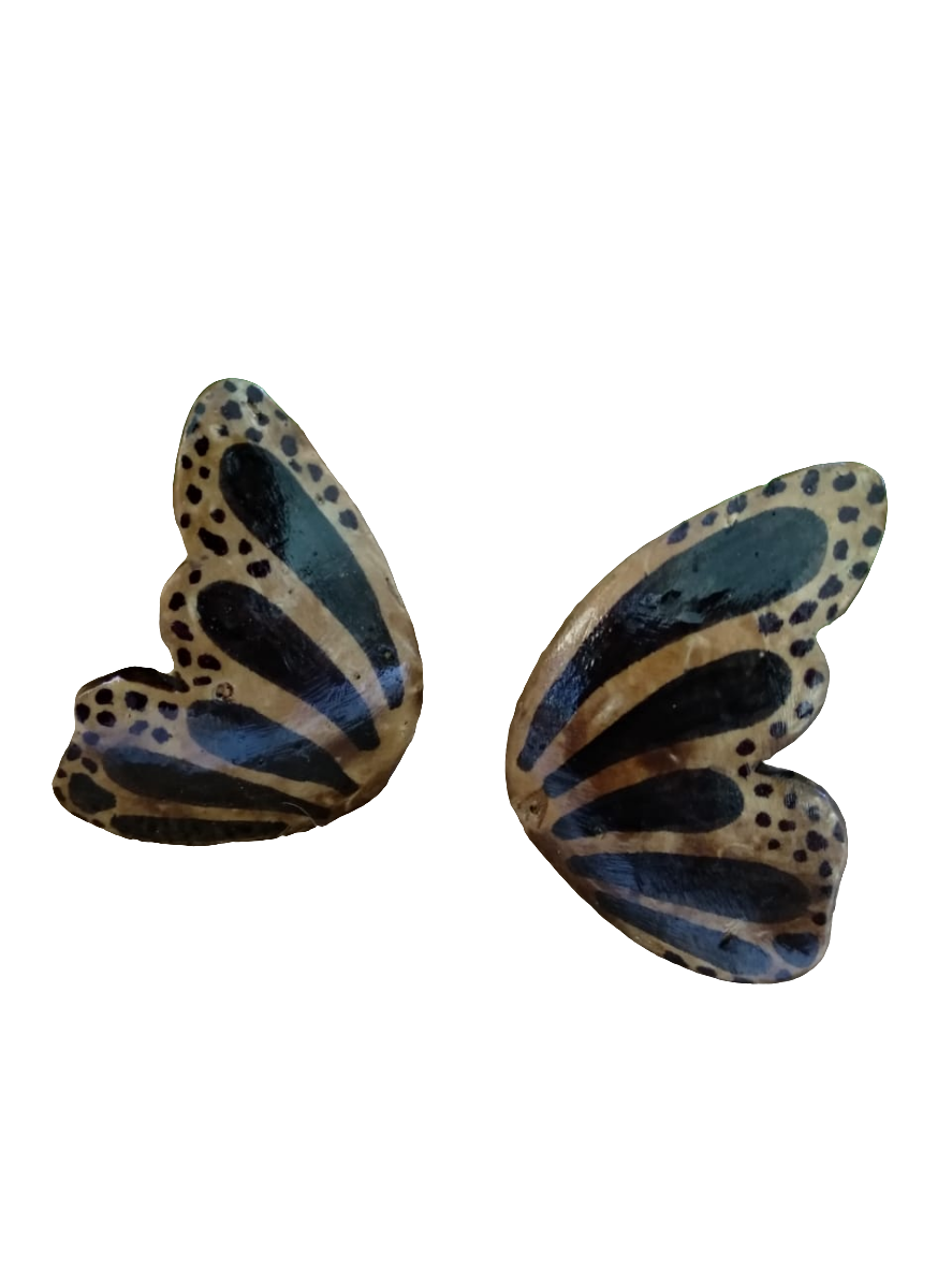 A pair of Mexican butterfly earrings with black, white, and gray colors, placed on a beige surface.