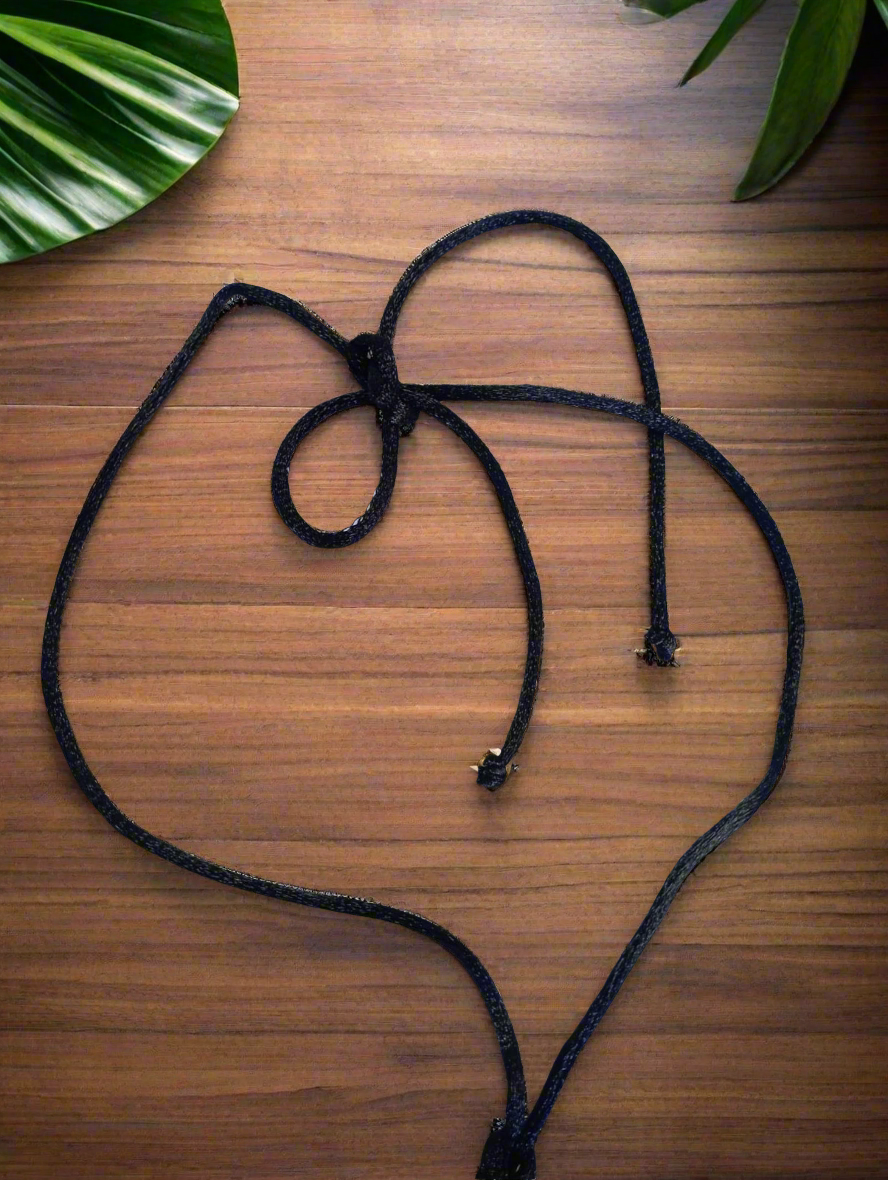 A set of brown leaf-shaped pendants and a necklace with a leaf pendant, displayed on a wooden surface with a green plant in the background.