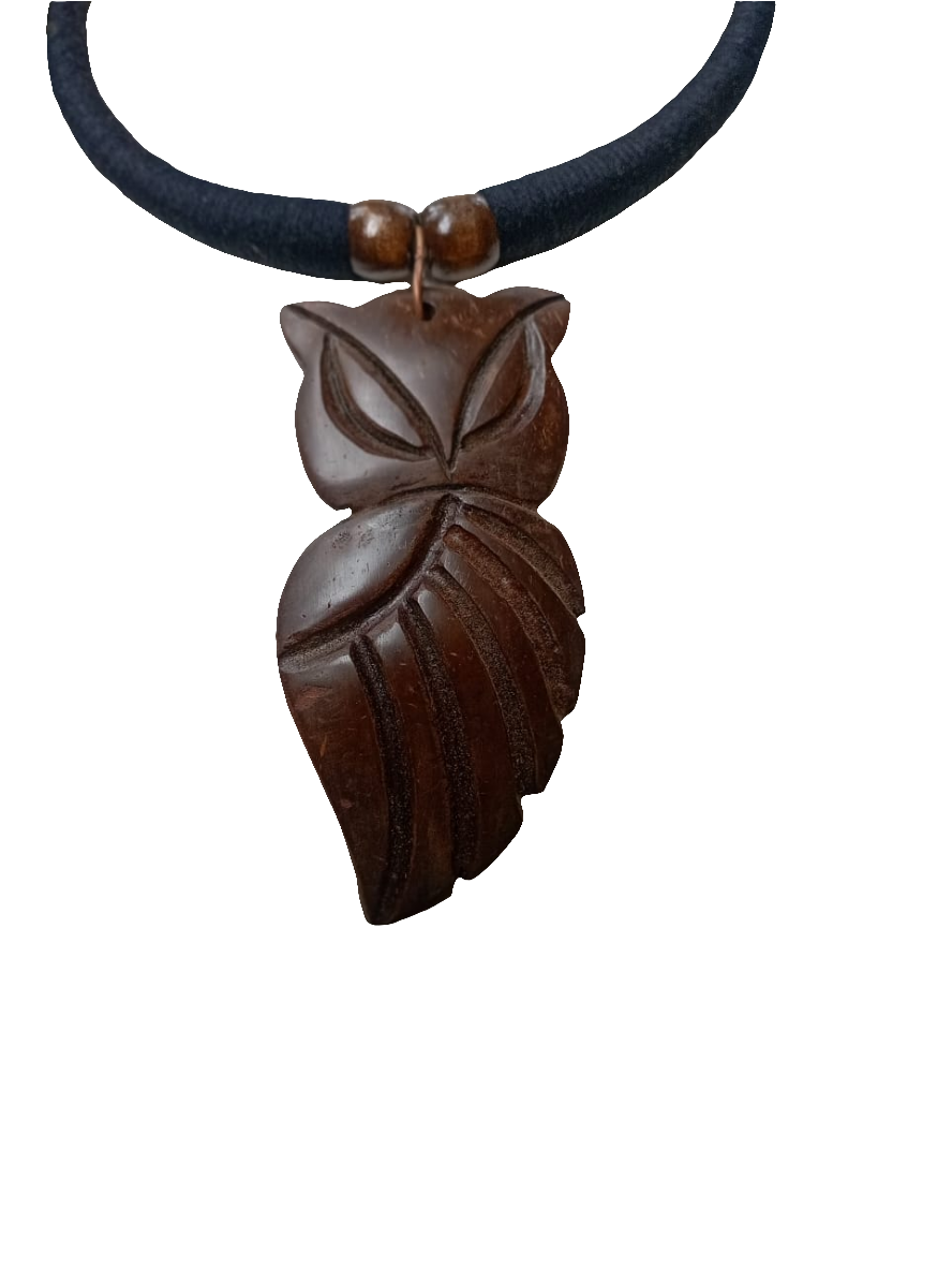 A brown necklace with a hand-carved owl charm displayed on a mannequin bust, set against a backdrop of greenery.