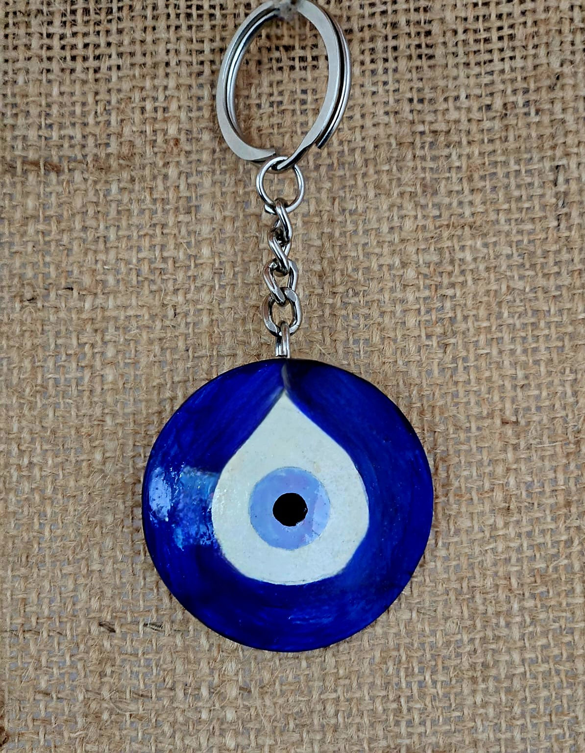 Blue and white evil eye keychain on a textured brown background