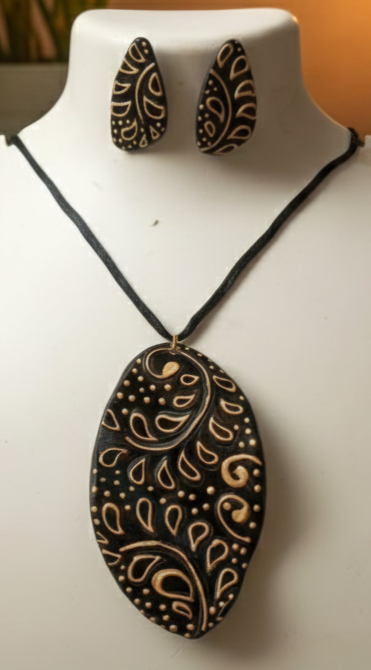Black and gold paisley-patterned necklace and earrings on a mannequin.