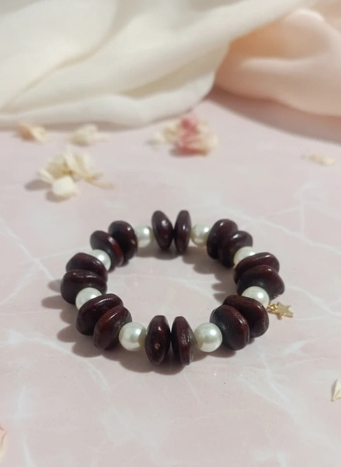 Bracelet with brown beads and pearls on a pink fabric background