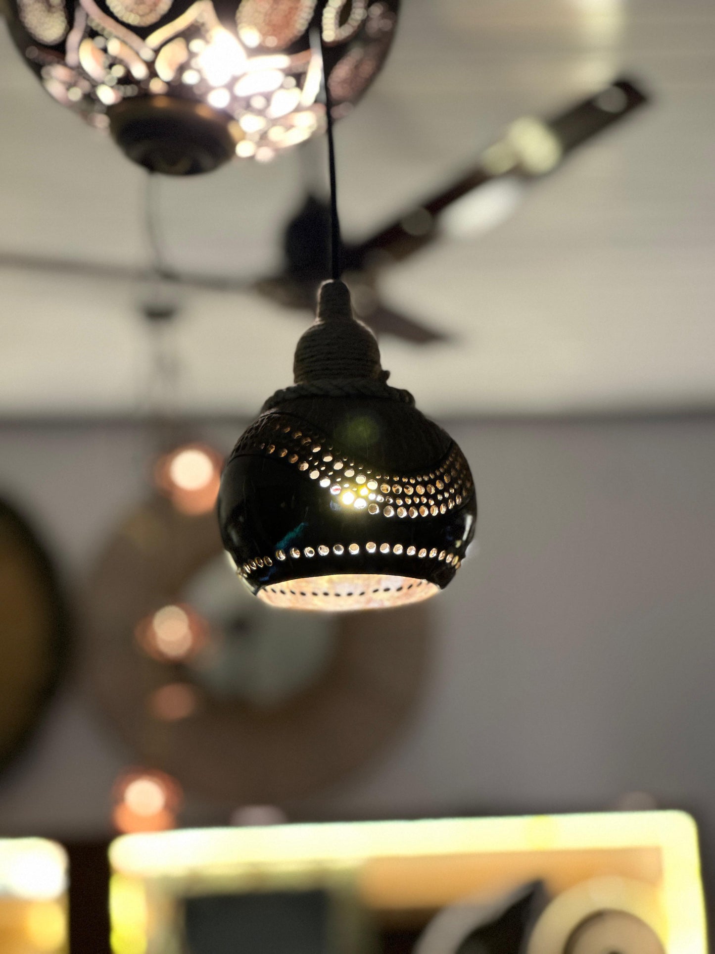 Decorative black pendant light with intricate design against a blurred background
