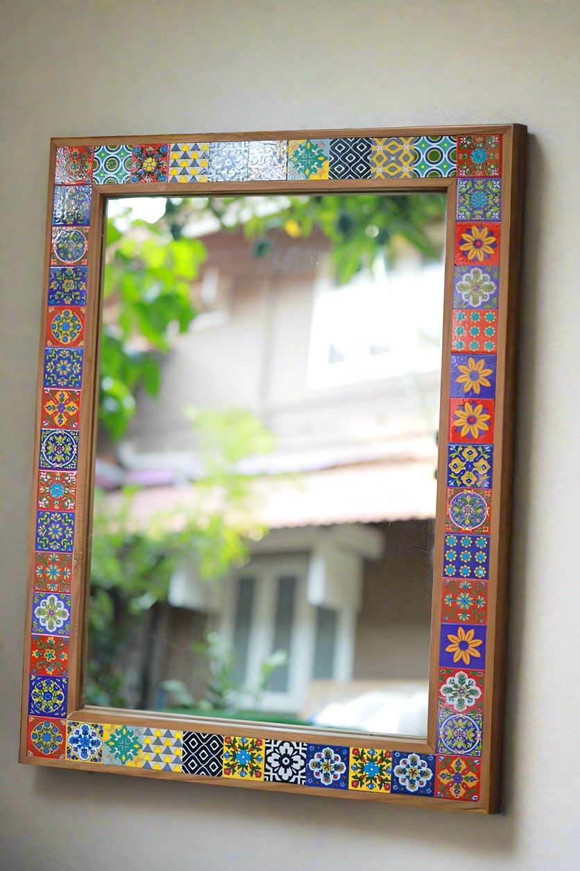 A rectangular mirror with a colorful geometric tile design on the frame, mounted on a wall.