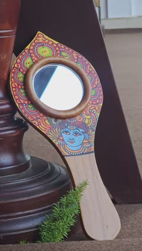 Decorative hand mirror with colorful design on a wooden stand