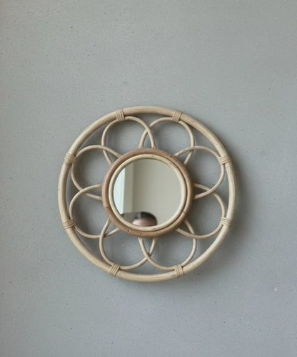 Round rattan mirror with decorative frame on a plain wall