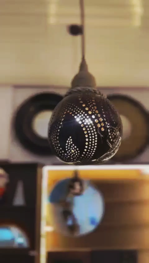 Decorative black pendant light with intricate design in a blurred indoor setting