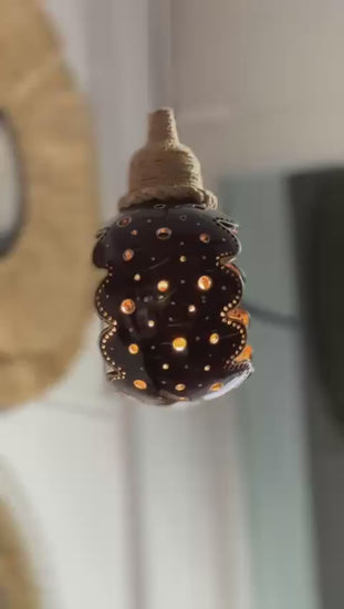 Decorative lamp with a textured surface and glowing interior, set against a blurred background.