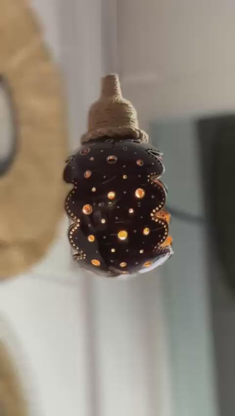 Decorative lamp with a textured surface and glowing interior, set against a blurred background.
