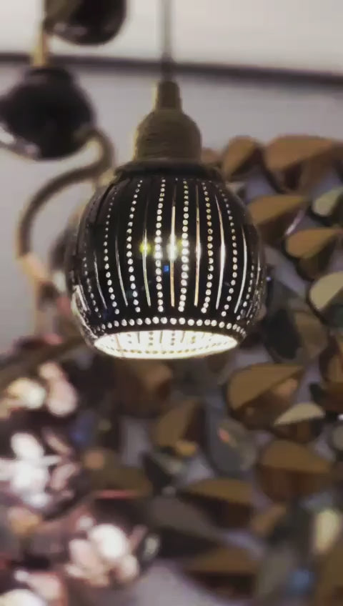 Decorative light fixture with a black and gold design on a blurred background