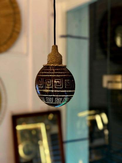 Decorative light bulb with intricate design hanging against a blurred background