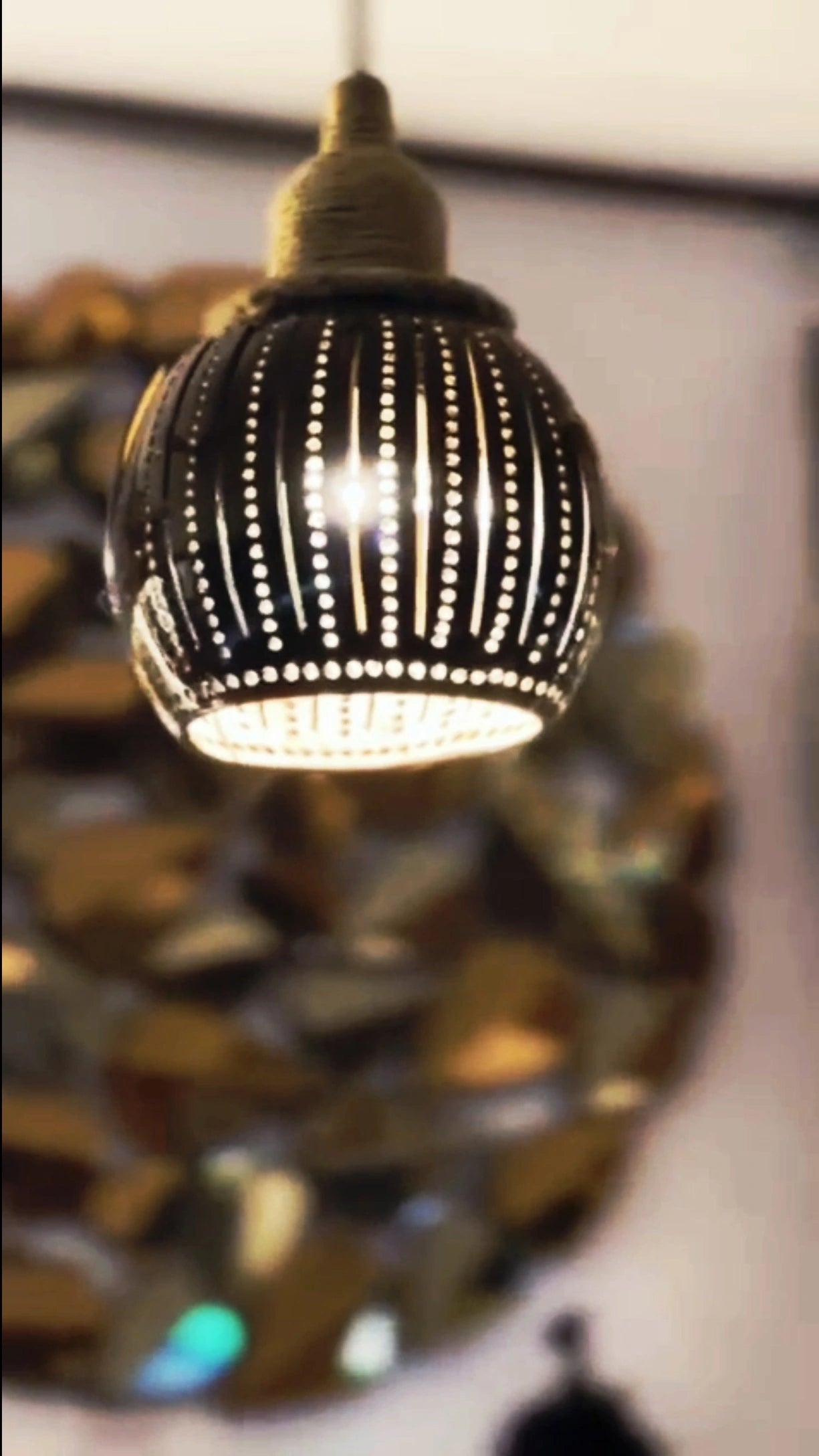 Decorative light fixture with a black and gold design on a blurred background