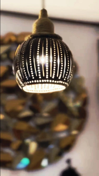 Decorative light fixture with a black and gold design on a blurred background