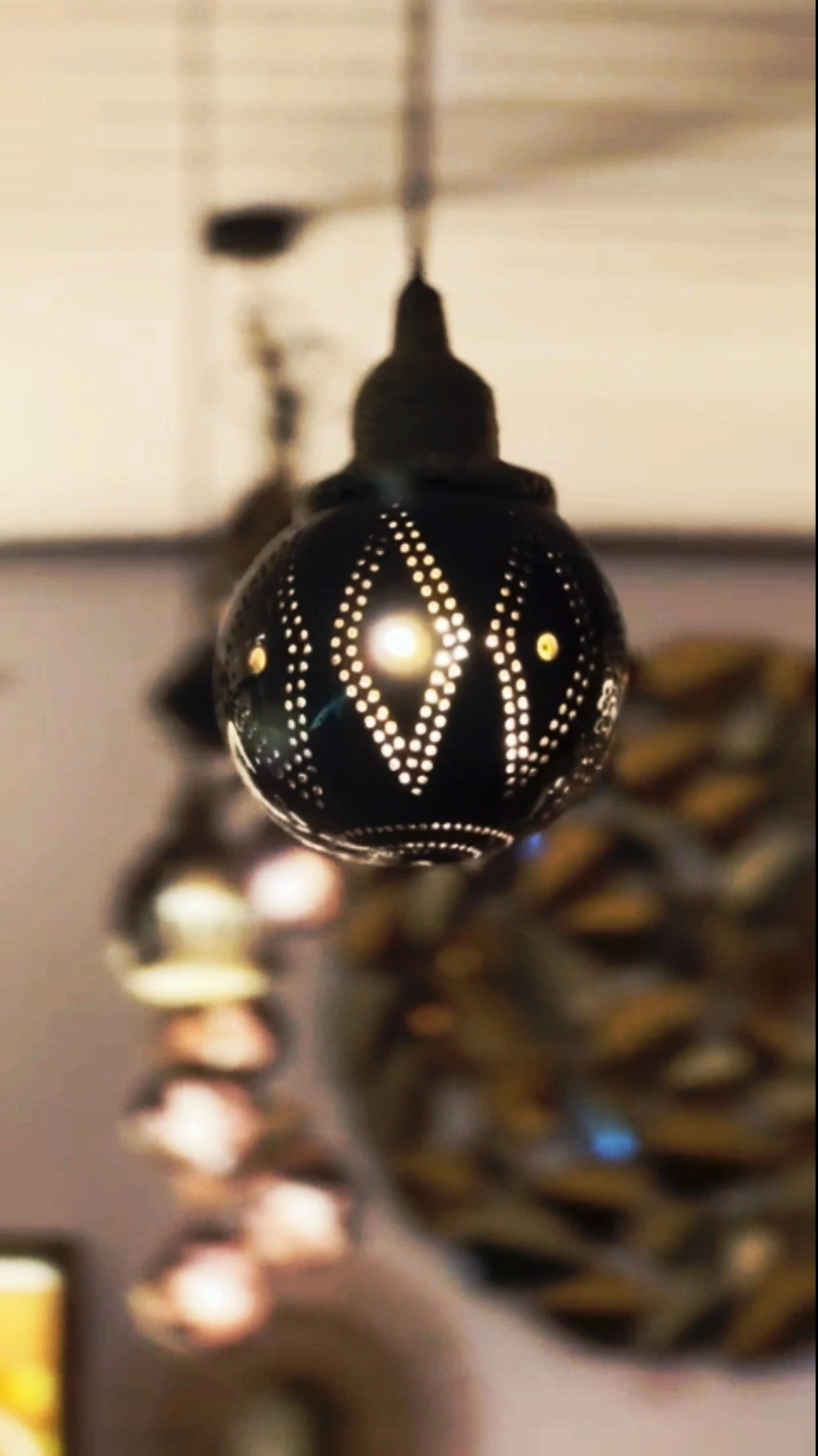 Decorative black lamp with intricate patterns hanging indoors.