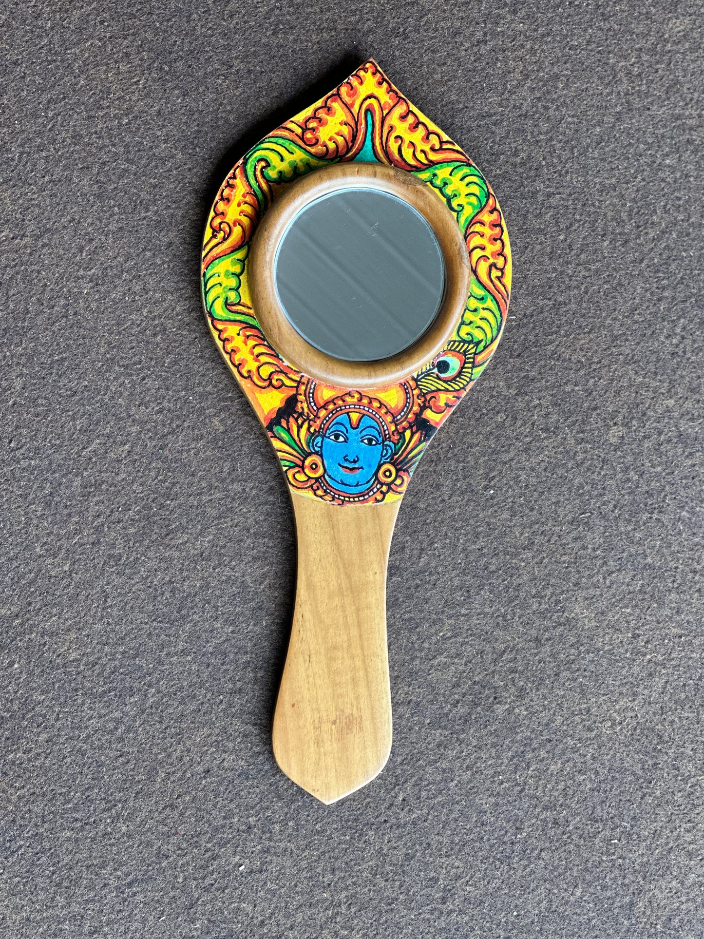 Decorative hand mirror with colorful design on a gray background