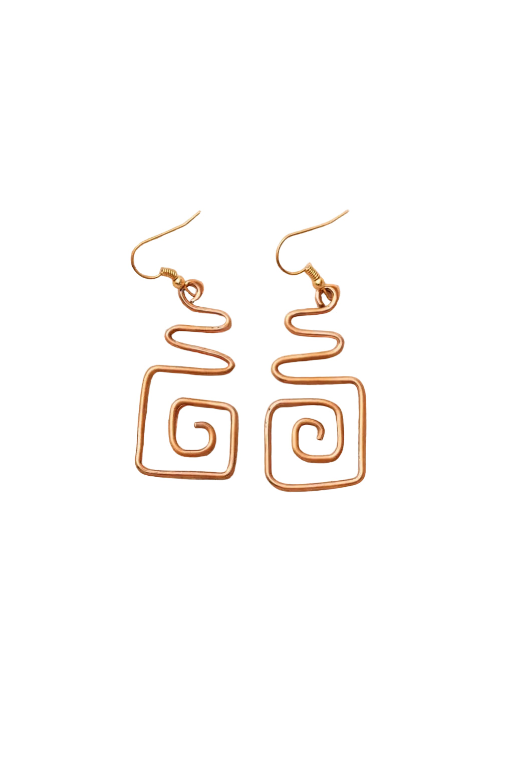 Gold spiral earrings on a sandy surface with dried flowers and rocks.
