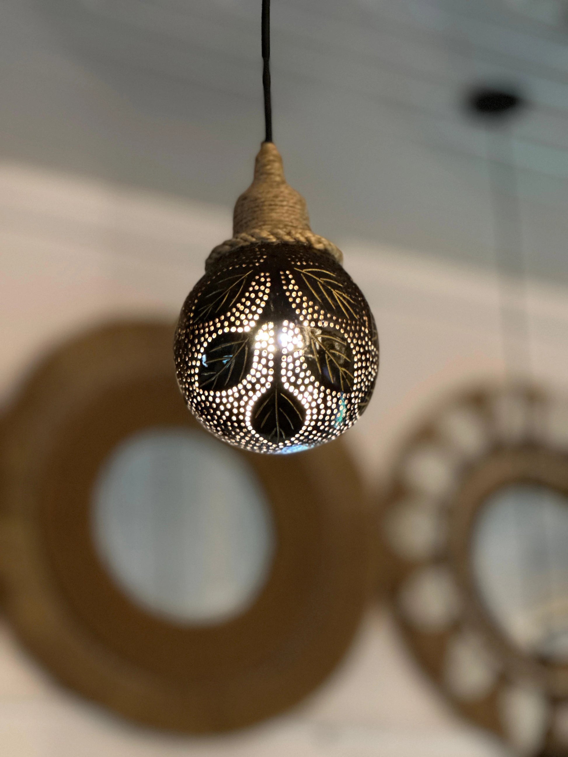 Decorative light bulb with intricate patterns hanging from a ceiling.