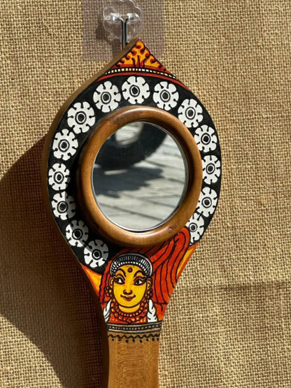 Decorative hand mirror with artistic handle on a textured brown background
