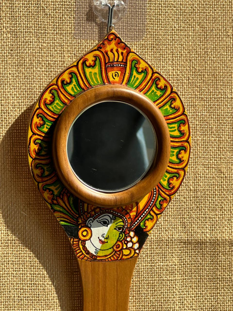 Decorative hand mirror with colorful patterns on a beige background