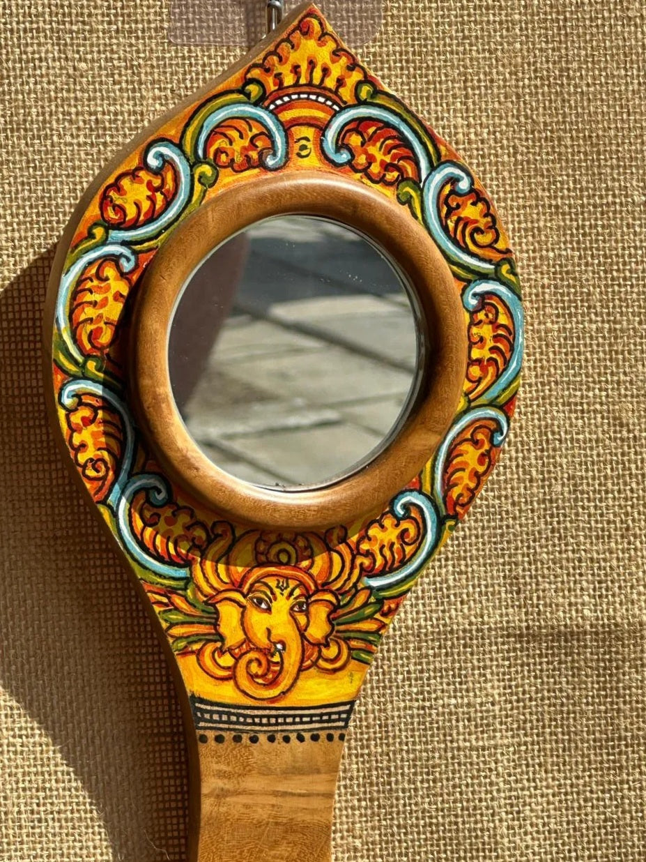 Decorative hand mirror with colorful patterns on a textured brown background