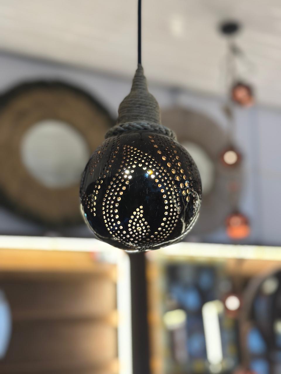 Decorative black pendant light with intricate design in a blurred indoor setting