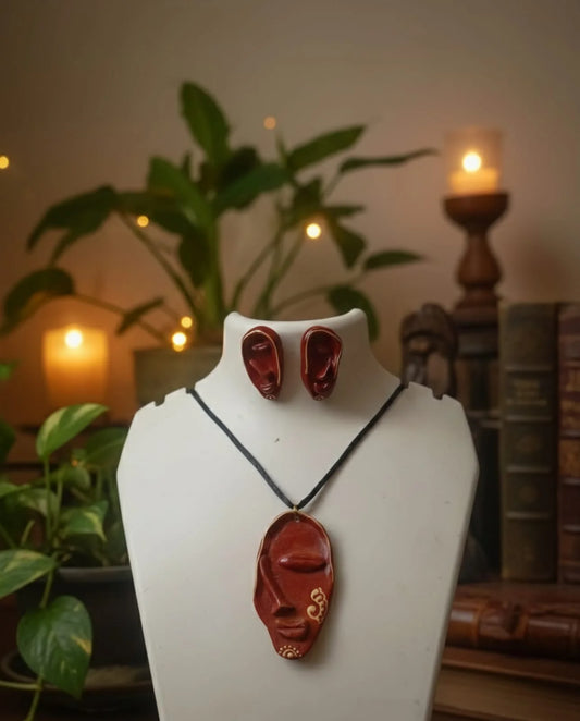 Jewelry set with pendant and earrings on a mannequin bust against a warm, indoor background.