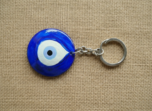Blue evil eye keychain on a beige fabric background