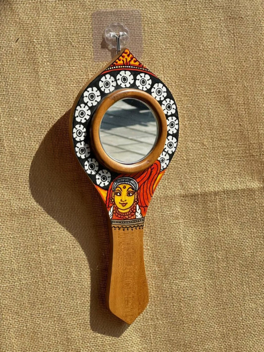Decorative hand mirror with a wooden handle and floral design on a beige fabric background
