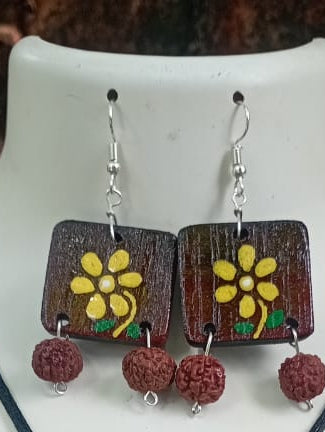 Wooden earrings with floral design and red beads on a white background