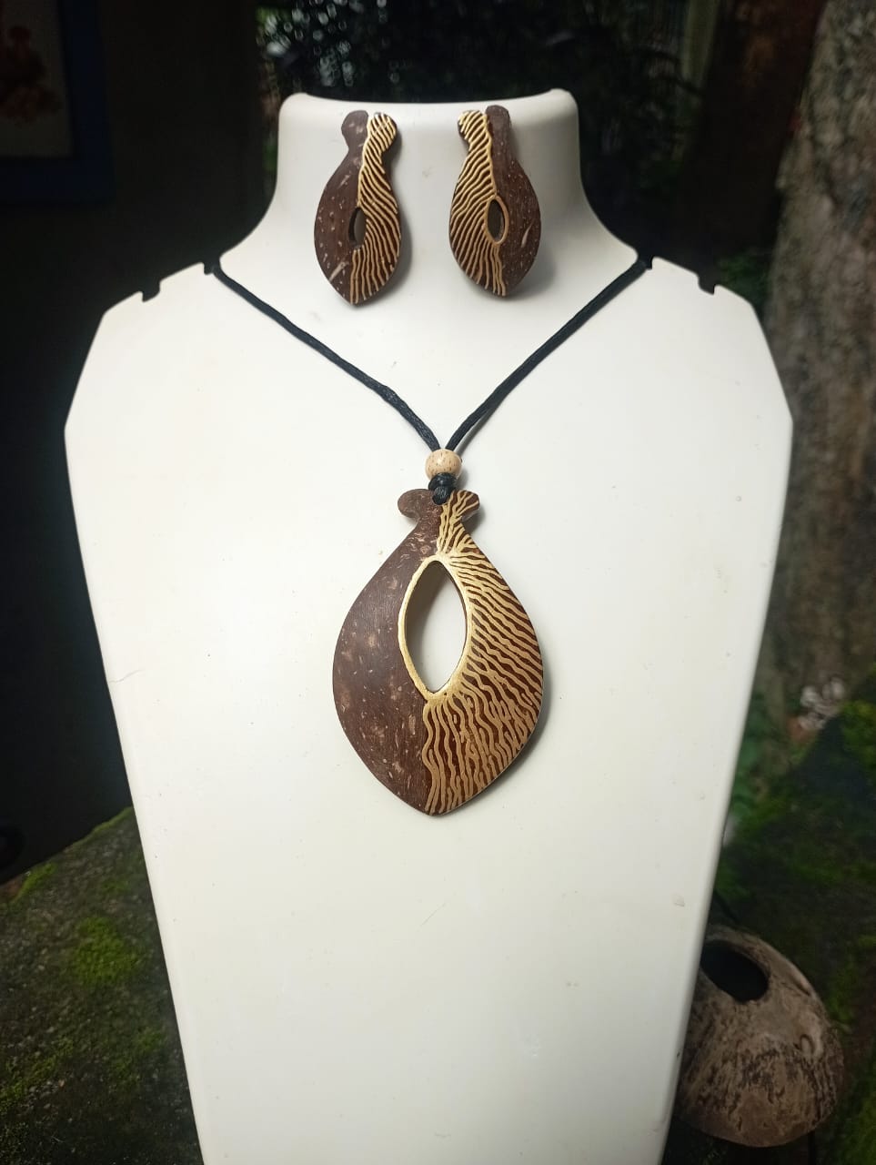 Jewelry set with pendant and earrings on a white stand.