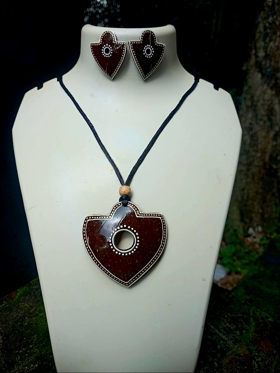 Jewelry set with heart-shaped pendant and earrings on a white stand.