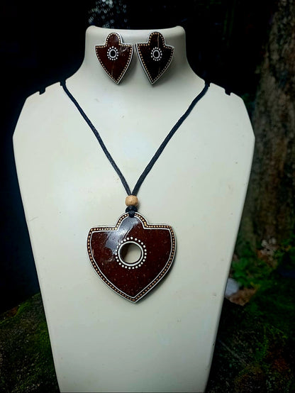 Jewelry set with heart-shaped pendant and earrings on a white stand.