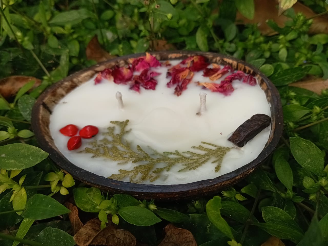 Candle in a coconut shell with natural elements on a grassy background