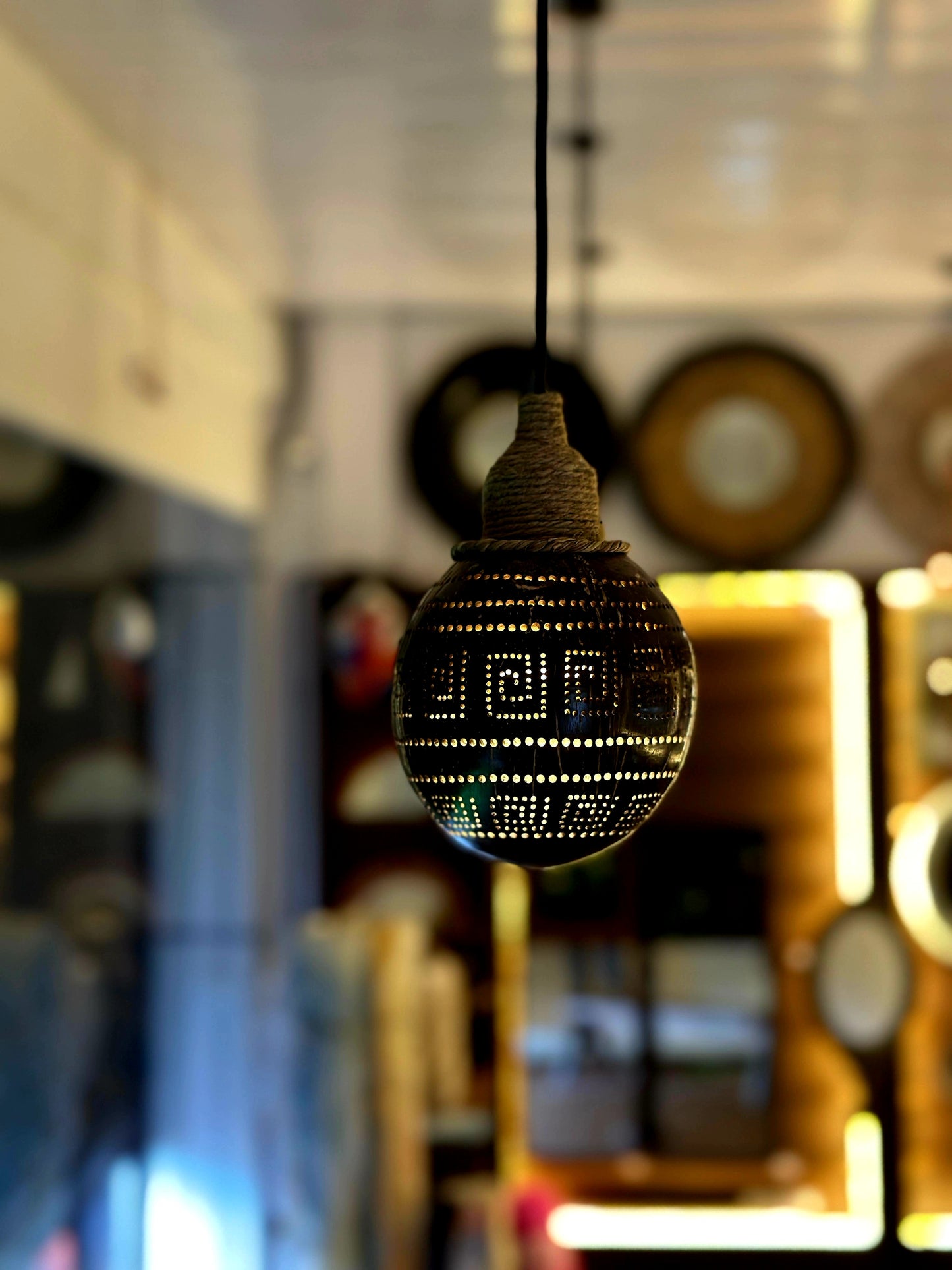Decorative light bulb with intricate design hanging against a blurred indoor background