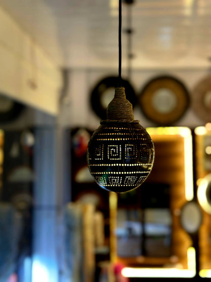 Decorative light bulb with intricate design hanging against a blurred indoor background