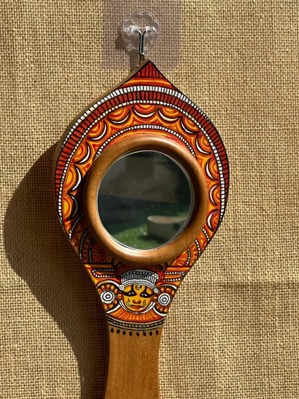 Decorative hand mirror with intricate designs on a beige background