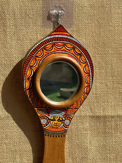 Decorative hand mirror with intricate designs on a beige background