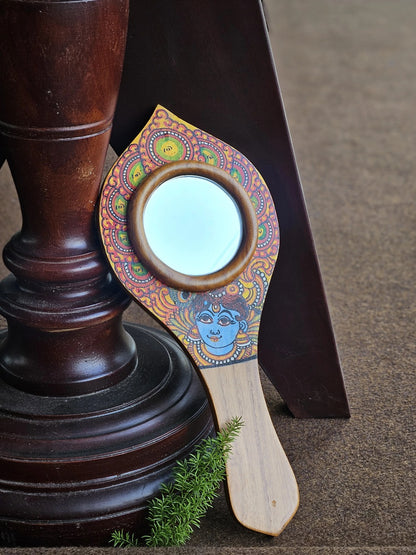 Decorative hand mirror with colorful design on a wooden stand